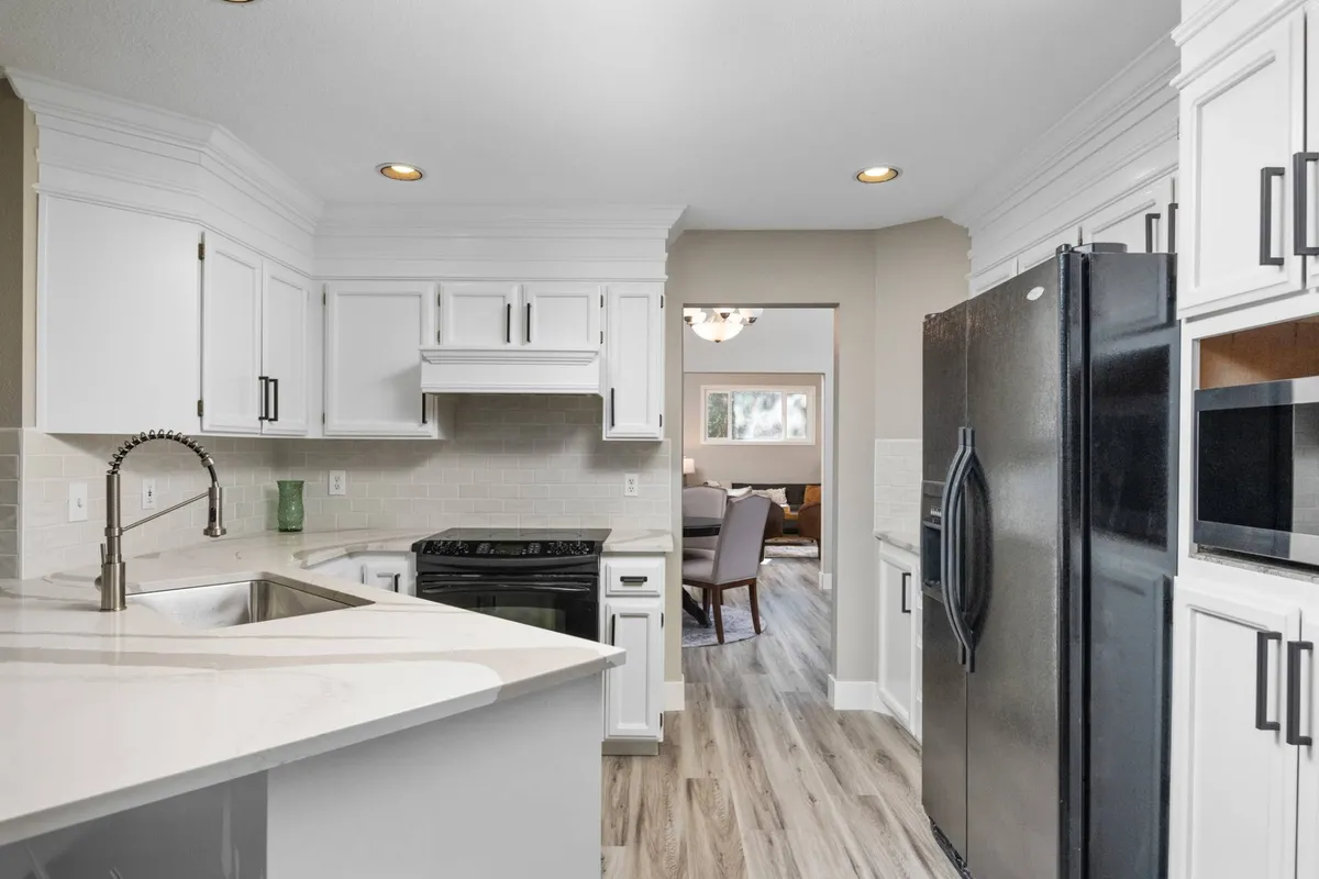 This image features a modern kitchen with a spacious island, stainless steel appliances, and bright white cabinetry. The setting is clean and functional, highlighting an area perfect for preparing everything from breakfast to elaborate dinners.